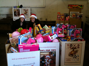 two employees smile next to boxes of toys