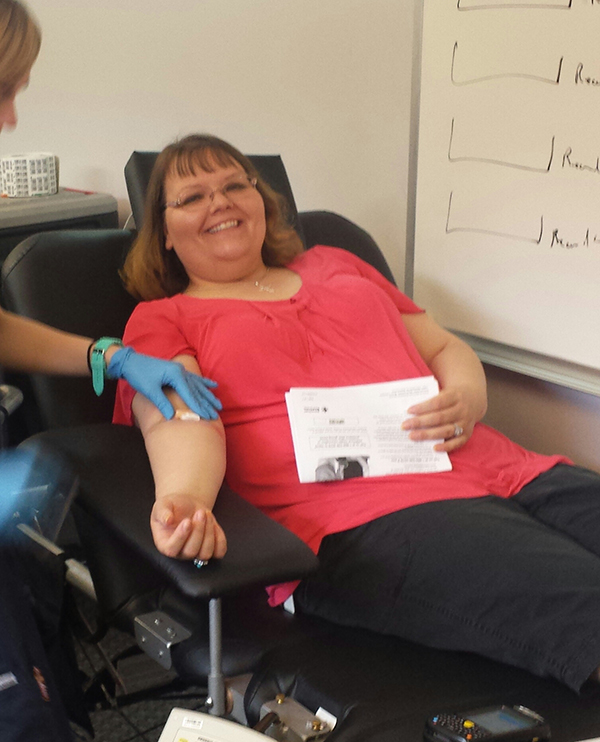 A woman smiles while preparing to give blood