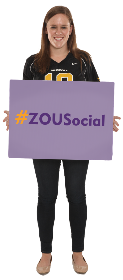 A woman stands holding a sign that says "#ZOUSocial"